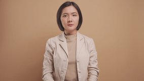 Asian business woman waving hands and say no isolated over beige background. 4K video