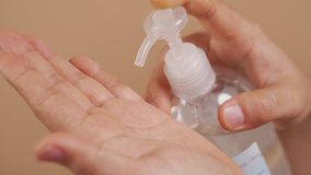Close up shot of woman 's hands putting hand sanitizer on hands for washing her hands isolated over beige background. 4K video