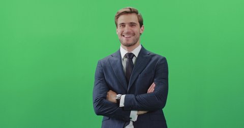Businessman in a suit standing in green room and looks at the camera, chroma key background, a man smiles, positive emotions.