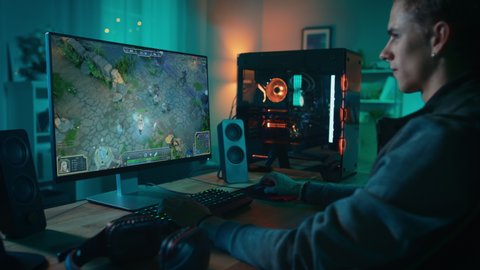 Professional eSports Gamer Plays RPG MOBA Mock-up Video Game with Lots of Action and Fun on His Powerful Personal Computer. Cyber Gaming Stylish Retro Neon Room