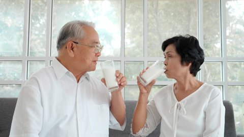 Portrait Asian senior elderly couple drinking milk on the sofa at home.