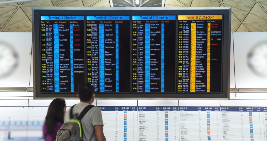 Time lapse. People in international airport looking at the flight information board, checking their flights. Tourists at international airport terminal flight timetable. Travel concept