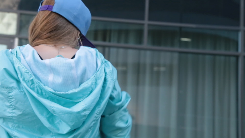 Girl is dancing modern hip-hop dance outdoors on the street in the city