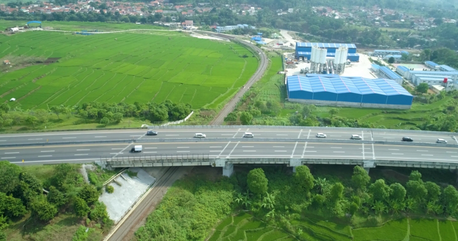 Scenic aerial view of a curved rail and rice field near cimeta bridge and  cipularang toll road, bandung, west java indonesia
