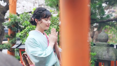 Young asian woman wearing kimono. Prayer in shrine. Japanese traditional clothes. Japanese translation: "shrine"