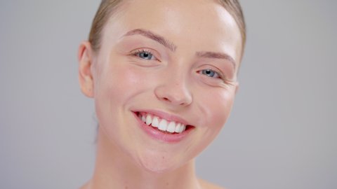 Close Up Of Beautiful Blonde Healthy Smile Woman Looking To The Camera And Laugh With Blue Eyes And Smooth Skin On Face In Slow Motion On A Grey Background Beauty Skin Care Concept