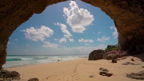 Beautiful view from mountain cave on tropical sand beach on background blue cloudy sky. 4K