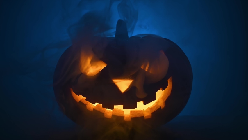 Happy Halloween. Scary glowing face of Halloween pumpkin in blue smoke. Selective focus | Shutterstock HD Video #1057916056