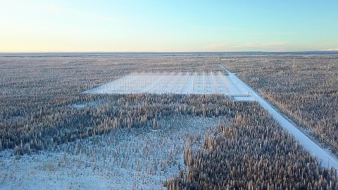 Aerial, drone shot, towards a field full of antennas, at the HAARP Alaska facility, on a cold and sunny, winter day, in Gakona, USA