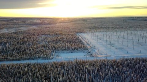 Aerial, pan, drone shot, of the HAARP antenna array, in middle of Alaskan woodlands, at sunset, on a sunny, winter evening, in Gakona, Alaska, USA
