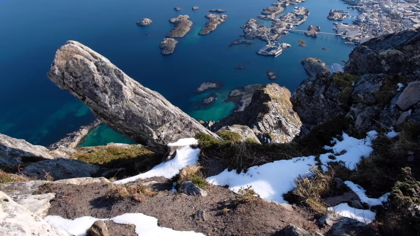 Camera tilts up to reveal horizon above Svolvaergeita. View of the blue ocean water. Norway.
