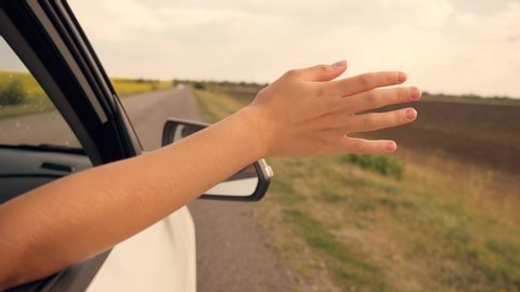 Girl hand in the car window. Girl travels with her family by car. Happy child travels. Happy family concept. Girl hand on the sun through the car window. Happy child in the car