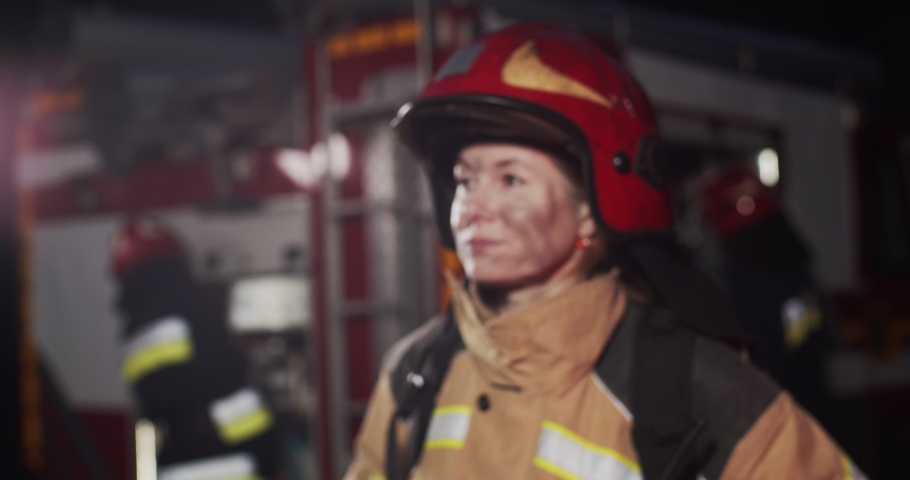 Close up portrait of face of mature Caucasian bwomrunette woman firefighter looking straight at camera at night and smiling. Concept of saving lives, heroic profession, fire safety Royalty-Free Stock Footage #1057927714