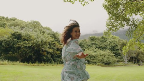 Attractive young woman running around in a park. Female in short floral dress running in the park.
