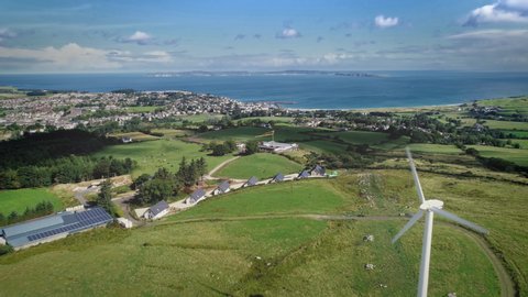 Ireland port town windmill aerial view on ocean bay. Beautiful landscape of green meadows, forests and similar white houses looking out seascape. Mesmerizing scenery shot of Ballycastle in 4K, UHD