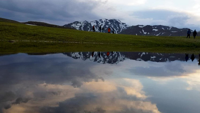 Clouds in Sky. Mountains and Meadow grassland reflected on clean pond in sunset afternoon time in Highland in Fresh Spring