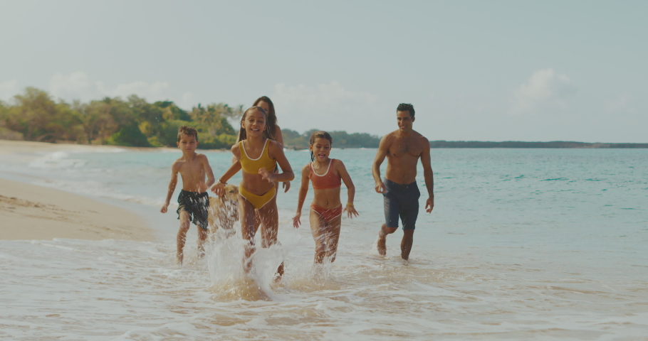 Happy young family playing and splashing on the beach with adorable golden retriever, family lifestyle | Shutterstock HD Video #1057932394