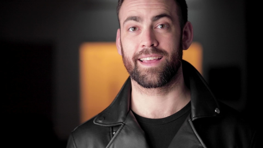 Bearded handsome man laughs into camera and goofily gesticulates, close up