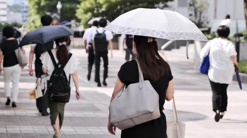 Japanese woman walking with a parasol on a hot summer day