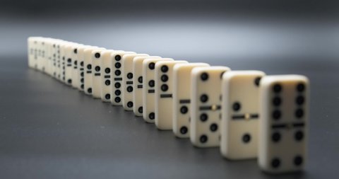 Falling dominoes. Chain reaction, built figure of dominoes falling in slow motion