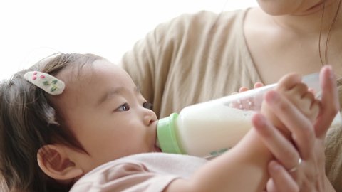 asian baby holding baby bottle and drinking milk 
