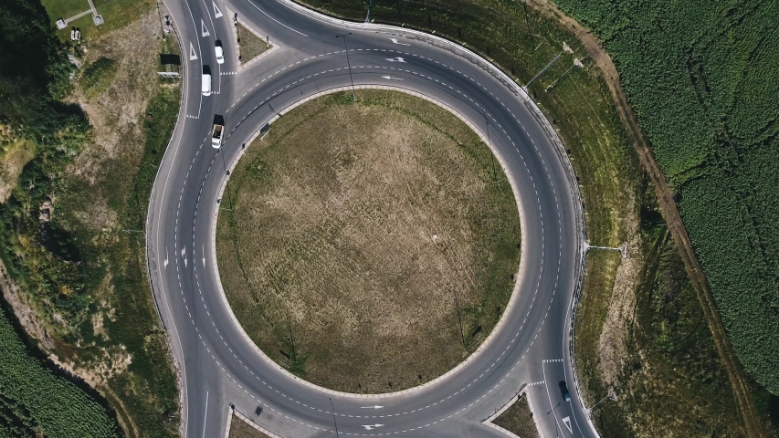 Roundabout traffic of cars and trucks on the circle ring road aerial top view Royalty-Free Stock Footage #1057937275