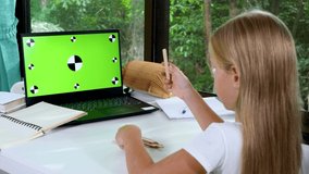 Kid girl does school homework using laptop at home. Video call by webcam on internet. Online or distance education. Teach math and counting in elementary school online. Display with green screen