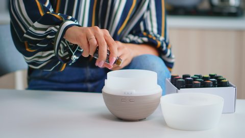 Close up of woman adding essential oils into diffuser. Aroma health essence, welness aromatherapy home spa fragrance tranquil theraphy, therapeutic steam, mental health treatment