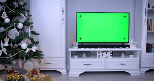 Smart tv with green screen near Christmas tree in living room. Using smart technology on holidays concept. 4k