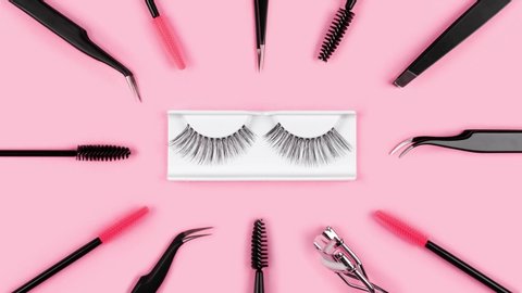 Makeup accessories. Fake eyelashes. Tools for eye lash extensions on trendy pastel pink background. Concept. Eyelash curler, tweezers, brushes, mascara. Cosmetic products. Animation. Beauty pattern.
