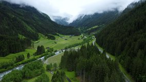 Aerial footage apline valley with river, road and pine tree forest. Tirol, Austria