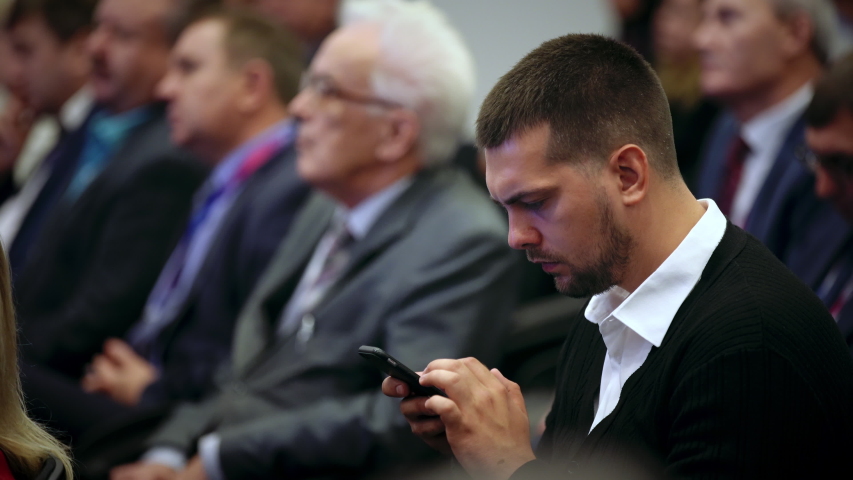 Person type touch screen crowded audience business forum. Viewer syposium listen speaker auditorium. Business man typing hand pad financial summit. Group people learning speech in crowd audience.