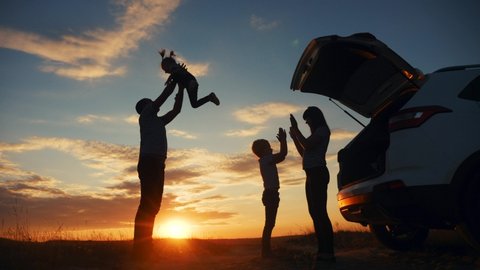happy family playing in the park silhouette at sunset next to the car journey. family travel kid dream concept. happy family stand with sunlight their backs watching in the park. friendly fun family