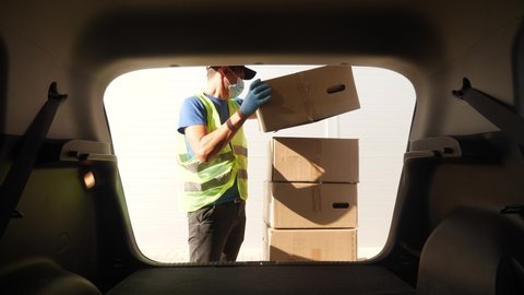 driver worker coronavirus. loader wearing a medical mask delivers goods during the coronavirus period. driver worker coronavirus. courier driver in gloves loads boxes during coronavirus