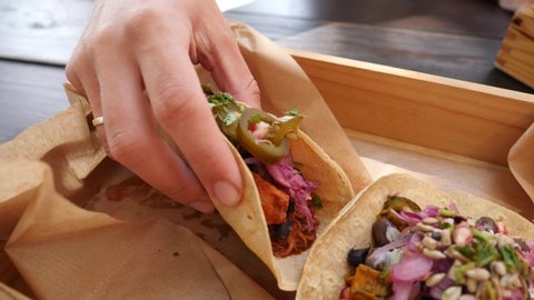 Female hand takes a tacos from a plate layout in mexican cuisine restaurant eating