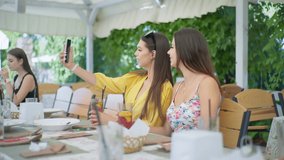 online communication, young girls in restaurant and talking with friend via video call on smartphone while sitting at table in cafe