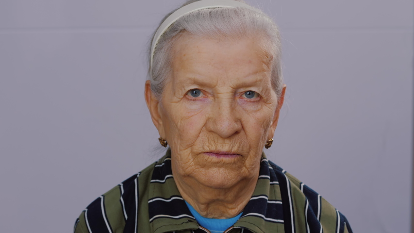 Close-up face of sad worry old woman with deep wrinkles looking at camera. Portrait of elderly depressed woman upset about middle age, pensive depressed. Royalty-Free Stock Footage #1057963795