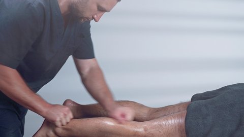 Male therapist giving leg and calf massage to athlete man. Sports physical therapy concept