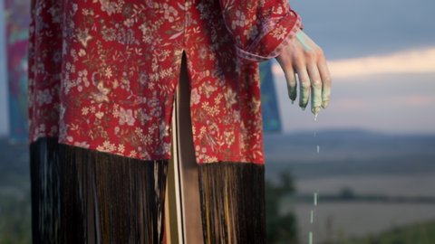 Image Of Woman Artist In Nature. Woman's Hand Dipped In Paint. Drops Of Paint Drip From It. Face Invisible. She Stands On Landscape Background With Blue Sky.
