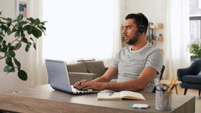 remote job, technology and people concept - man with headset and laptop computer having video conference at home office