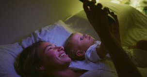 Authentic shot of happy neo mother and her newborn baby are using technology tablet for family entertainment in a bed before asleep. Concept of technology, new generation,family, connection,parenthood