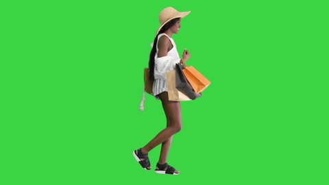 Happy african american woman in straw hat walking with shopping bags on a Green Screen, Chroma Key.