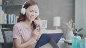 Young Asian woman use digital tablet for online learning, video conference or working at home. New normal healthy lifestyle at home concept. 