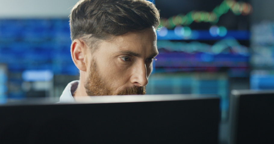 Close up of young Caucasian mman trader working at monitor computer and browsing online in trading office. Male broker following rates and bets. Manager texting at screen. Royalty-Free Stock Footage #1057979548