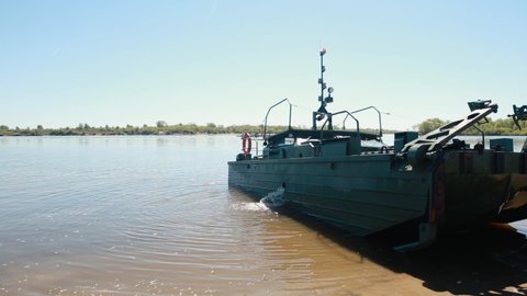 A military boat stands on the banks of the river.