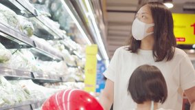 4K video 2 year old kid and mom with face mask in supermarket. Concept for life in outbreak and new normal.