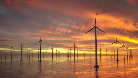 Wind turbines spinning in the ocean. Isolated Windmill farm, aerial view at dusk with sun setting.