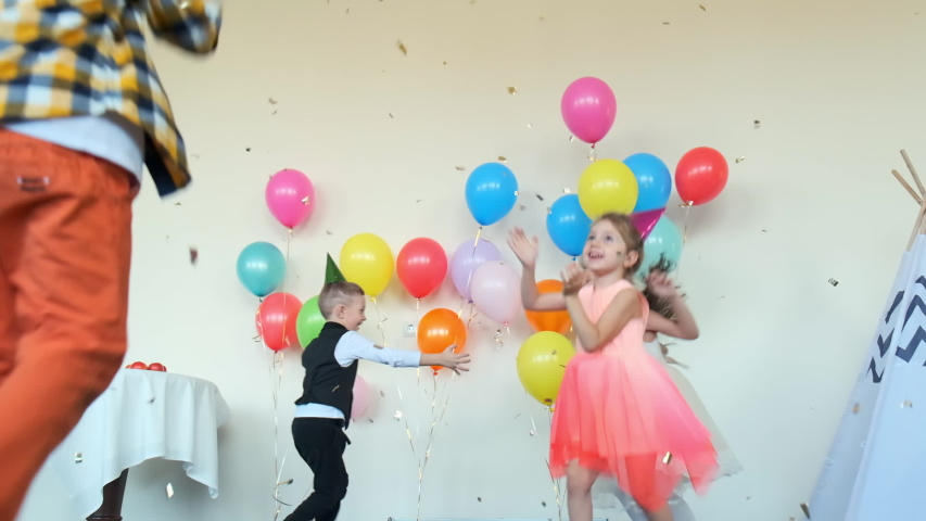 joyful little boys and girls dance in decorated room with wigwam and color balloons at funny birthday party slow motion Royalty-Free Stock Footage #1057996153