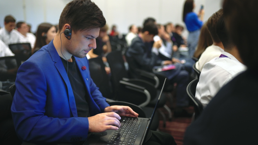 Person type keyboard crowded audience business forum. Viewer conference listen speaker auditorium. Businessman typing notebook financial summit. Group people learn education speech in crowd audience