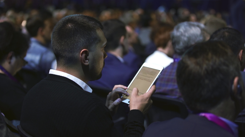 Crowded students study conference business man audience college. Education auditorium person typing touch pad. Studying crowd type text touching screen. Audience group people listen educational speech